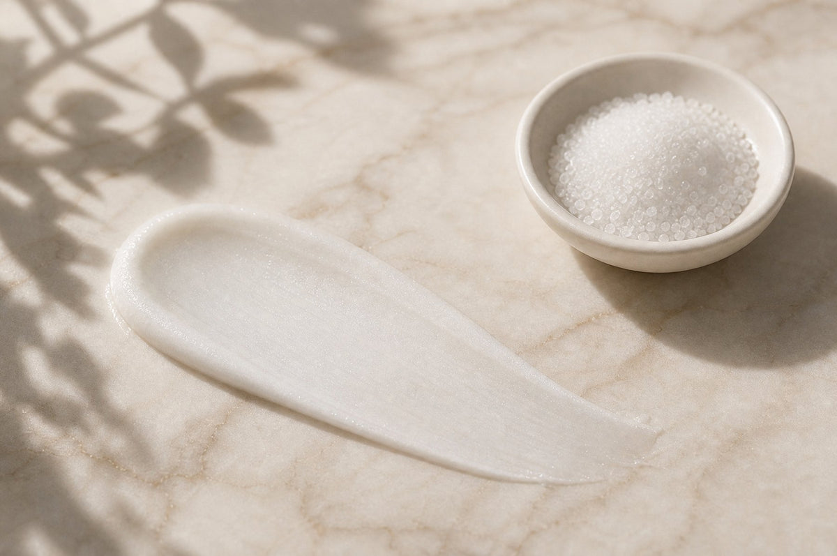 Glatt verstrichene helle Paste und feine Mineralkörner in einer Schale auf Marmor